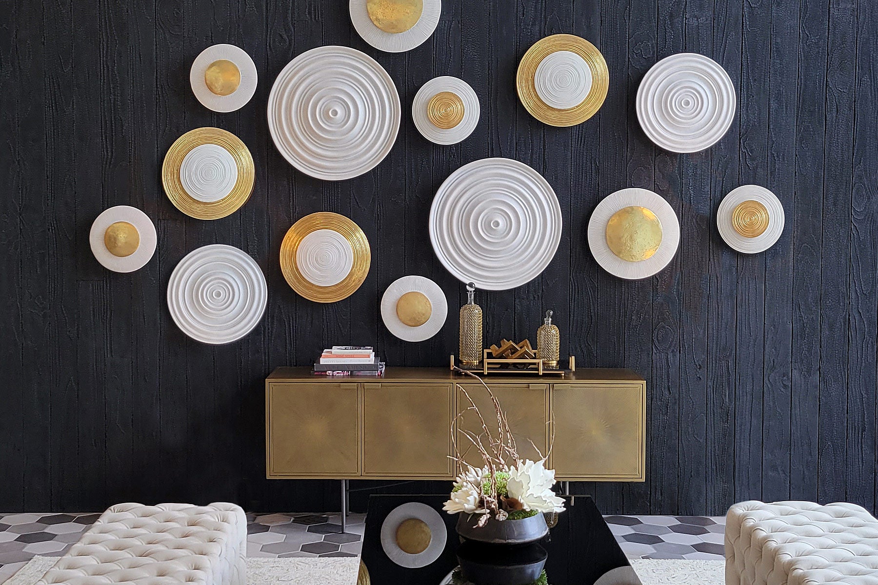 Gold and white circular Wall Art on a black wood wall above a gold console table.