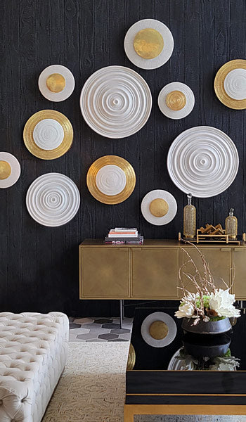 Gold and white circular Wall Art on a black wood wall above a gold console table.
